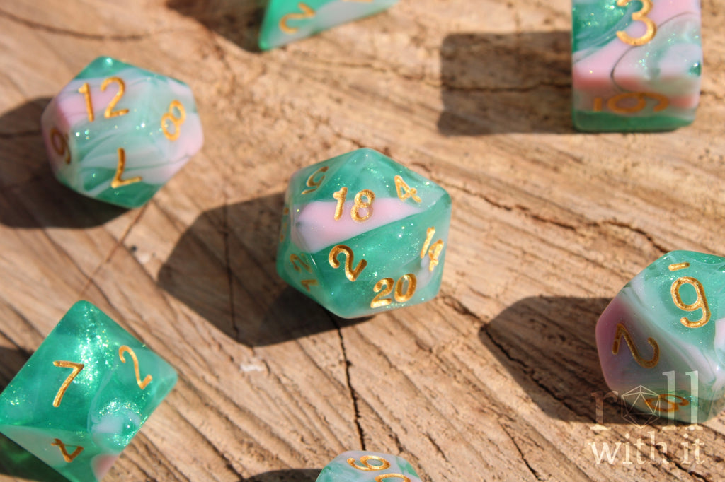 Set of colorful glittery teal green and pink polyhedral dice on a wooden surface