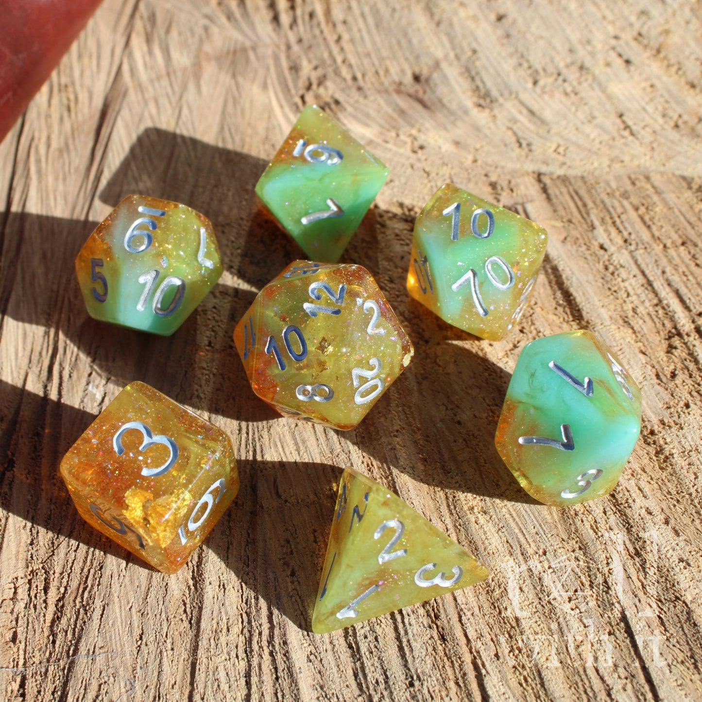Set of green and orange gold foil polyhedral dice on a wooden surface