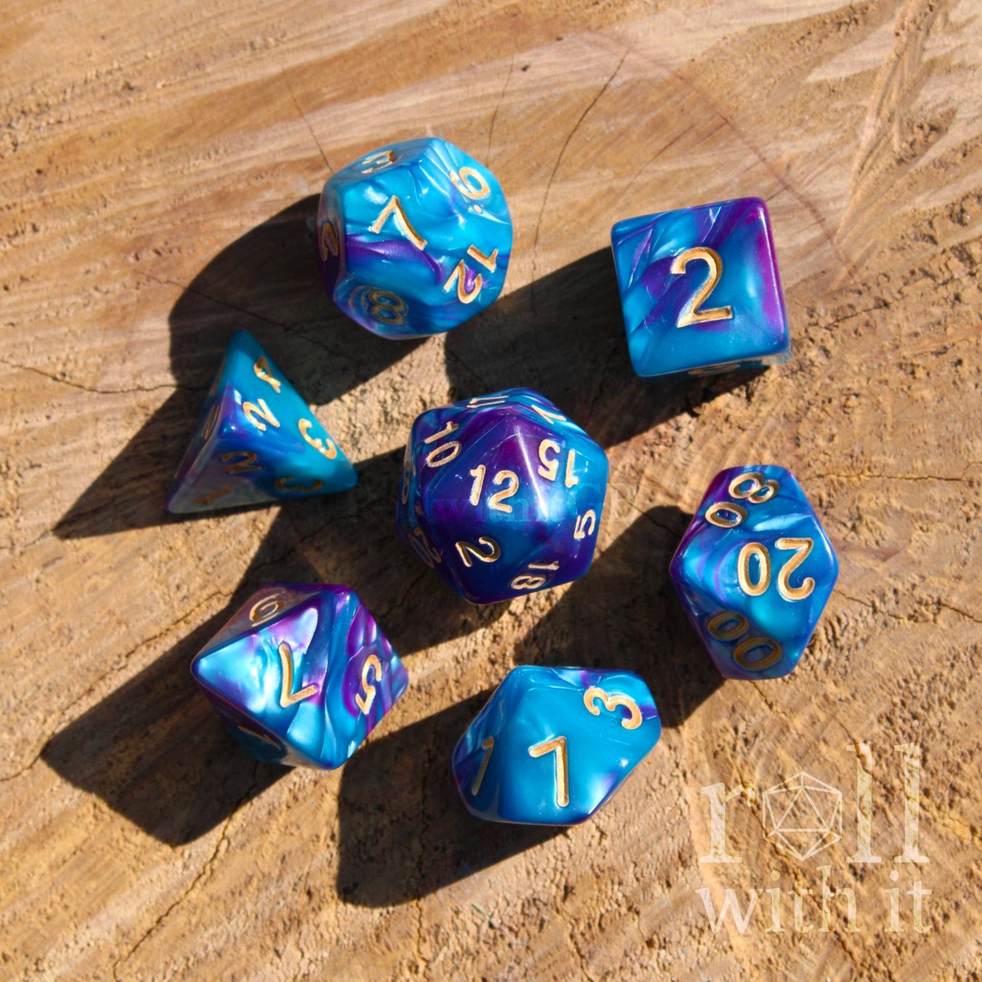 Set of bright ultramarine blue and purple polyhedral dice with gold numbers on a wooden surface.