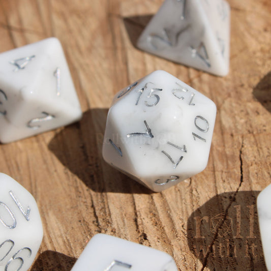 Granite White resin polyhedral roleplaying dice with silver numbers on a wooden surface