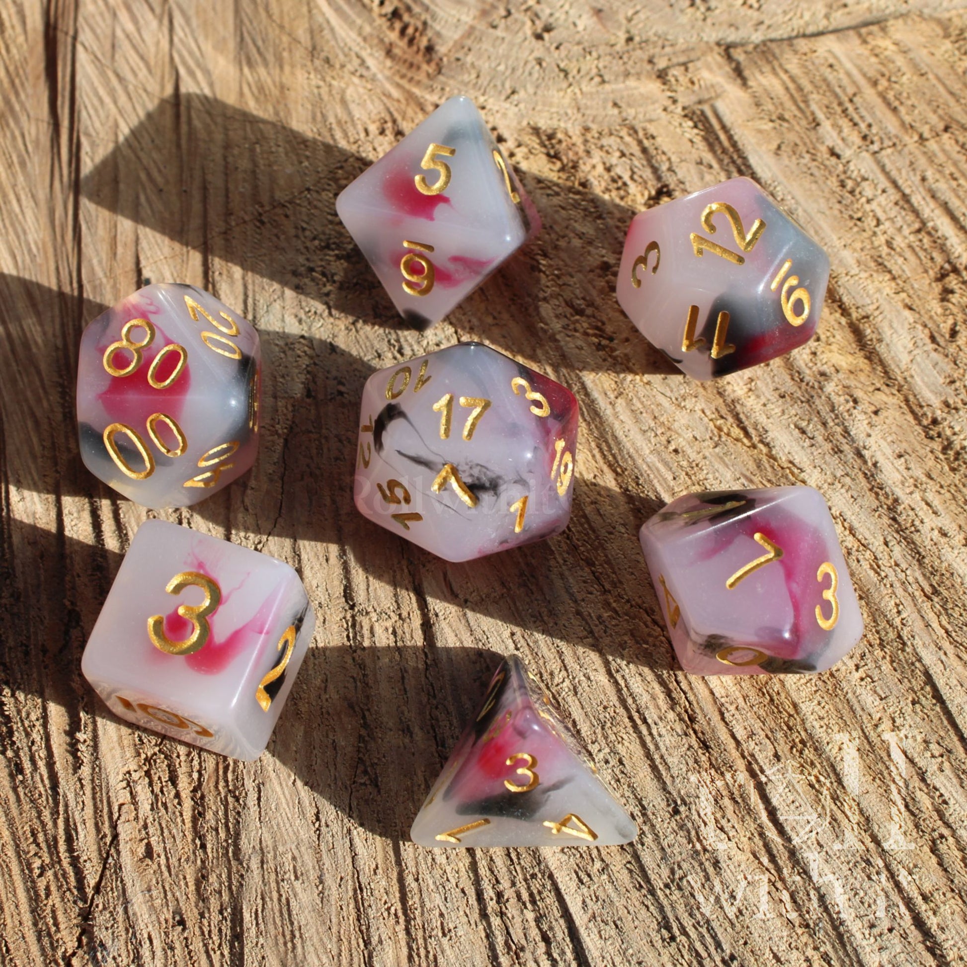 Set of dice with pink and white marbled pattern on a wooden surface