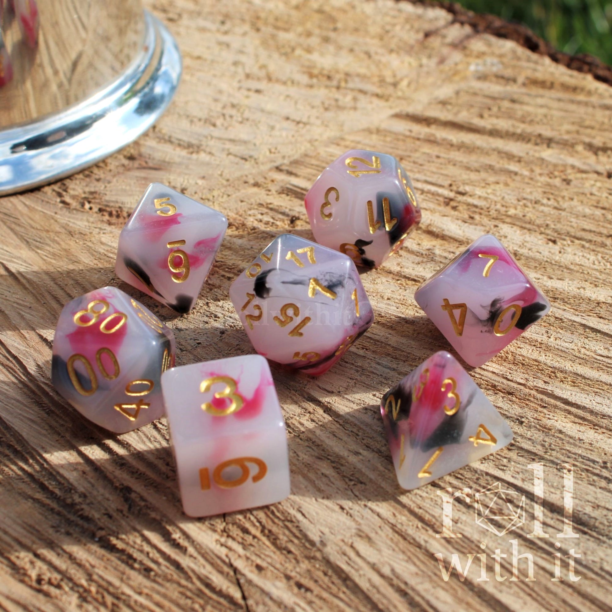 Set of pink and milky white dice with floral designs on a wooden surface