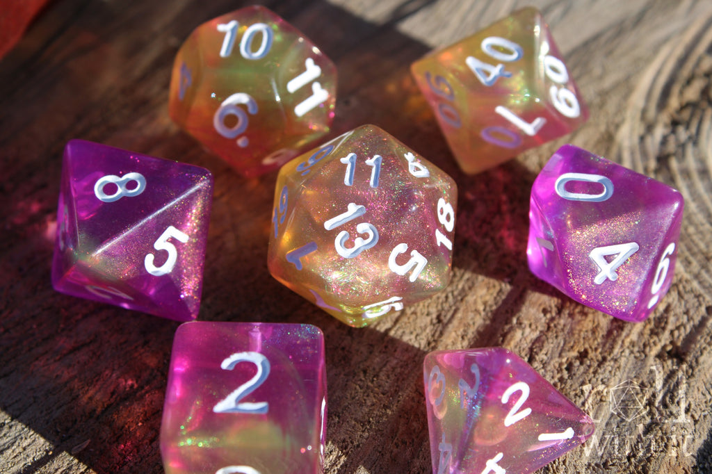 Set of colourful purple pink and yellow glittery polyhedral roleplaying dice on a wooden surface
