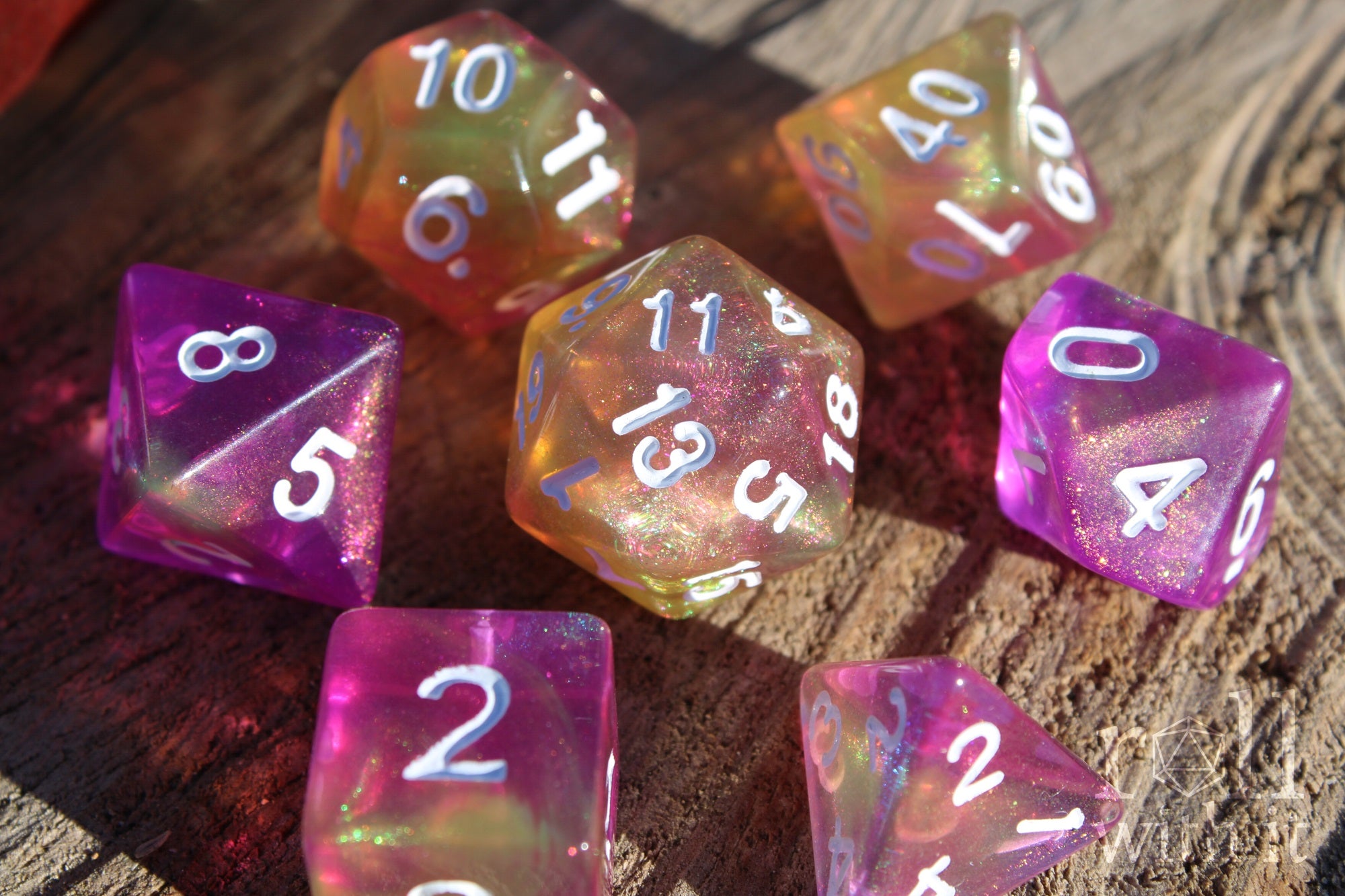 Set of colourful purple pink and yellow glittery polyhedral roleplaying dice on a wooden surface