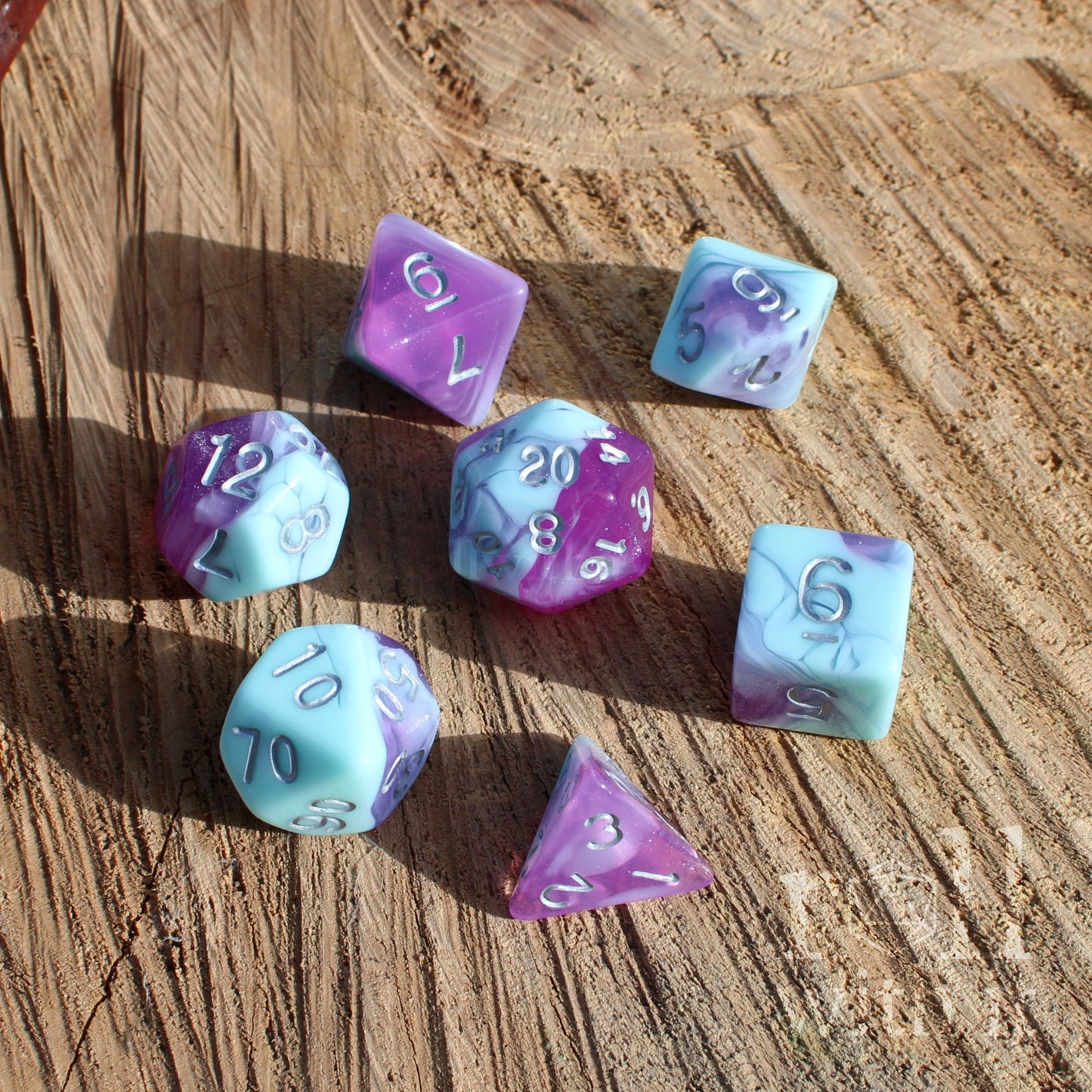 Set of multicolored lilac baby blue pale dnd polyhedral dice on a wooden surface