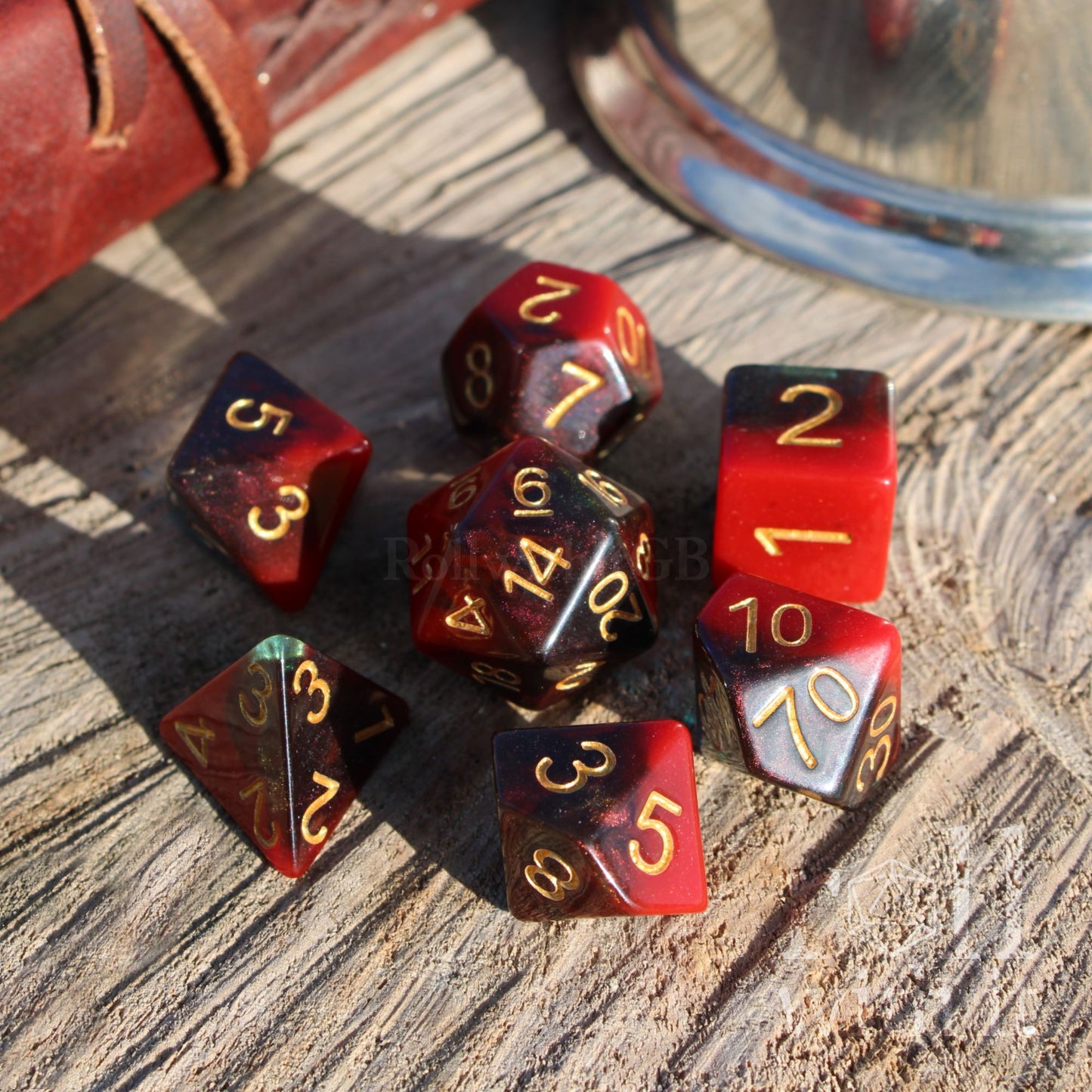 Set of polyhedral dice with red and dark blue colors and green glitter on a wooden surface