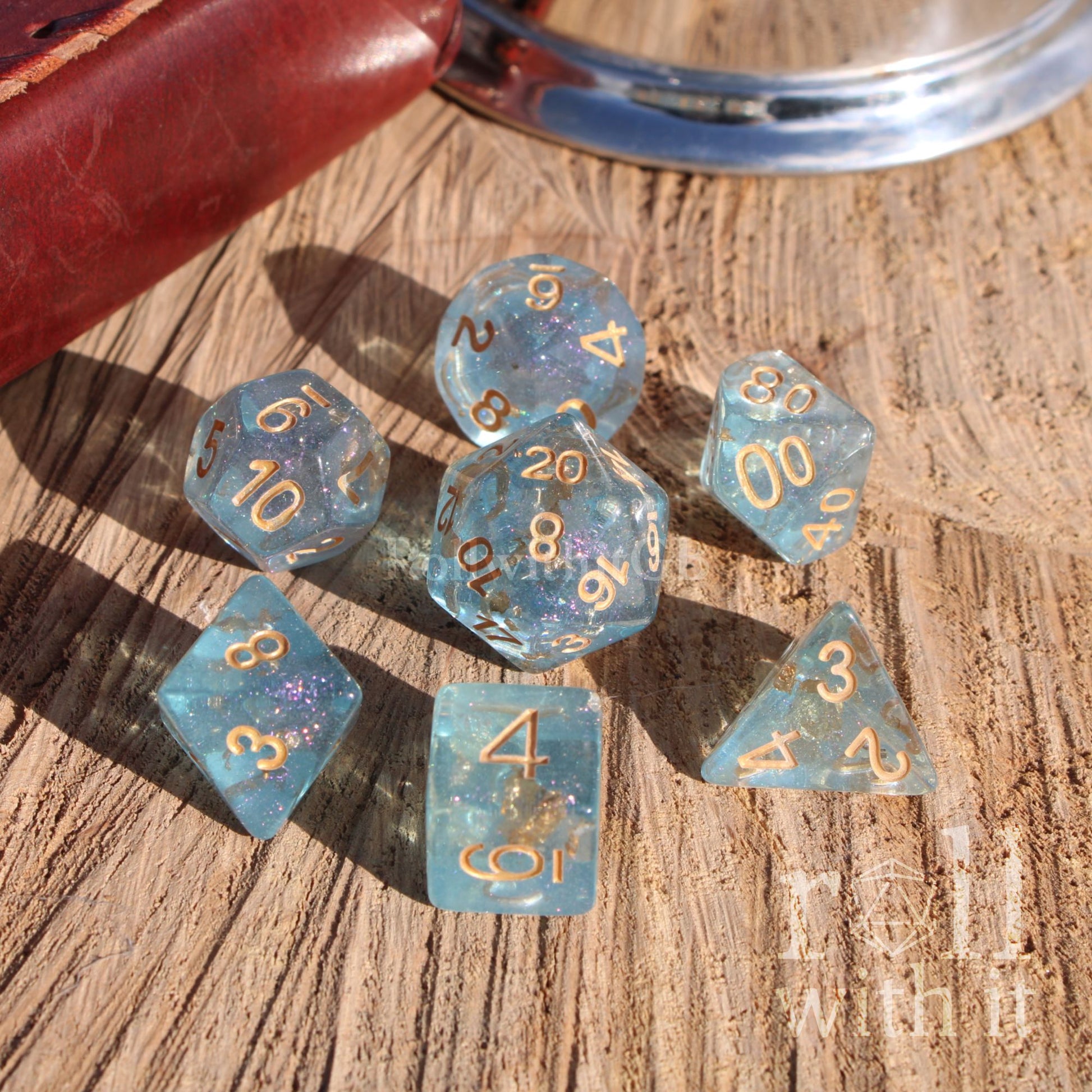 Set of pale blue dice with gold numbers on a wooden surface
