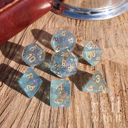 Set of pale blue dice with gold numbers on a wooden surface