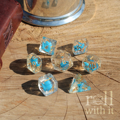 A set of 7 cute balance blue whale dice on a wooden surface with golden numbers