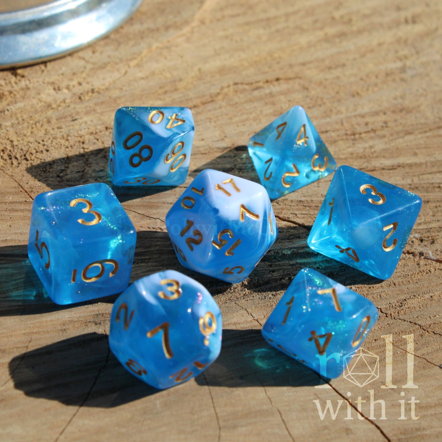 Set of blue mixed with glitter and white polyhedral dice with gold numbers on a wooden surface