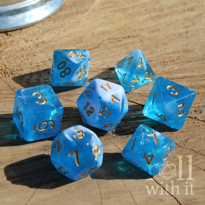 Set of blue mixed with glitter and white polyhedral dice with gold numbers on a wooden surface