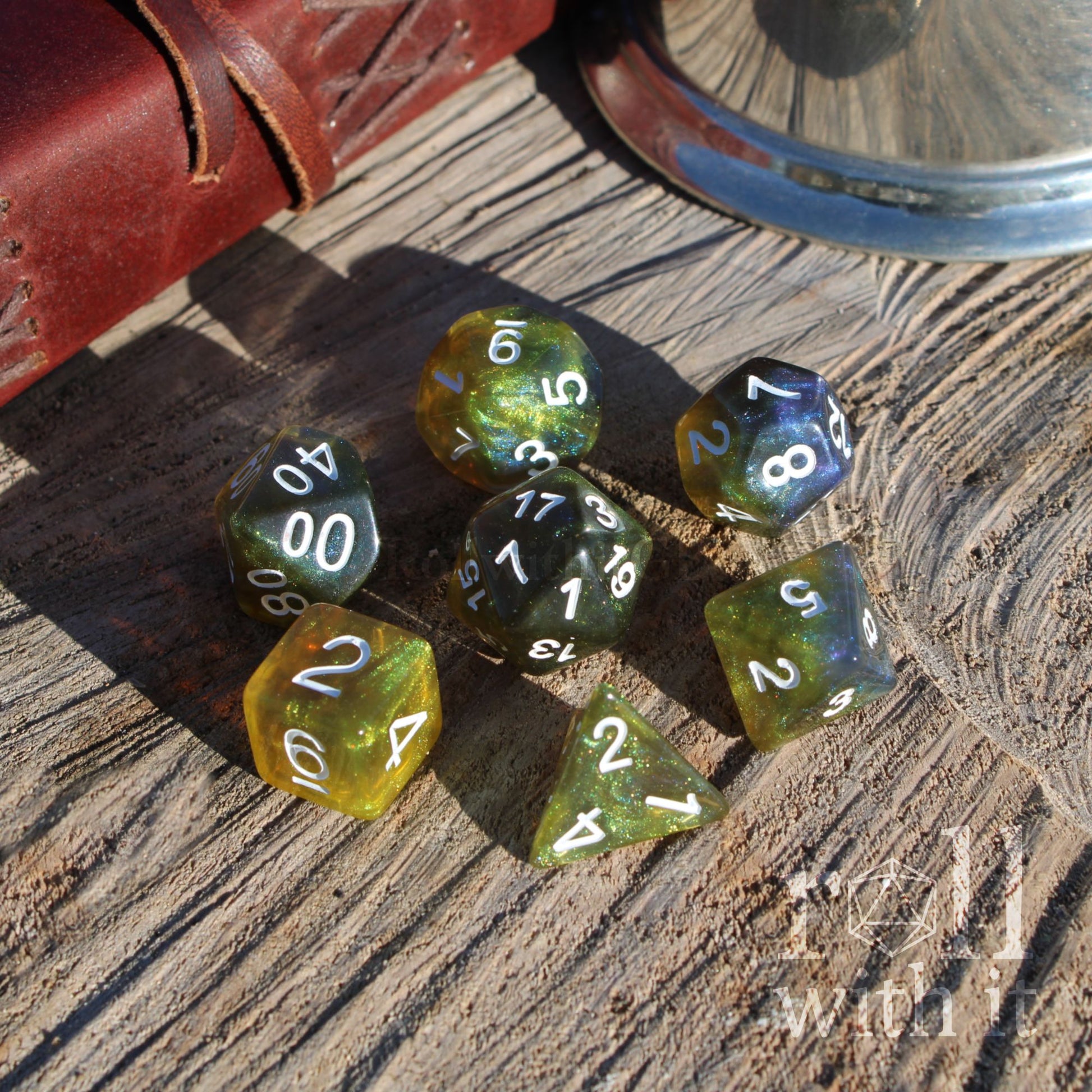 Set of blue yellow bog green polyhedral dice on a wooden surface with a leather case in the background.