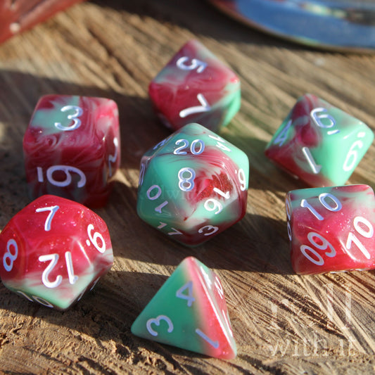 Set of cherry red and mint green polyhedral dice on a wooden surface