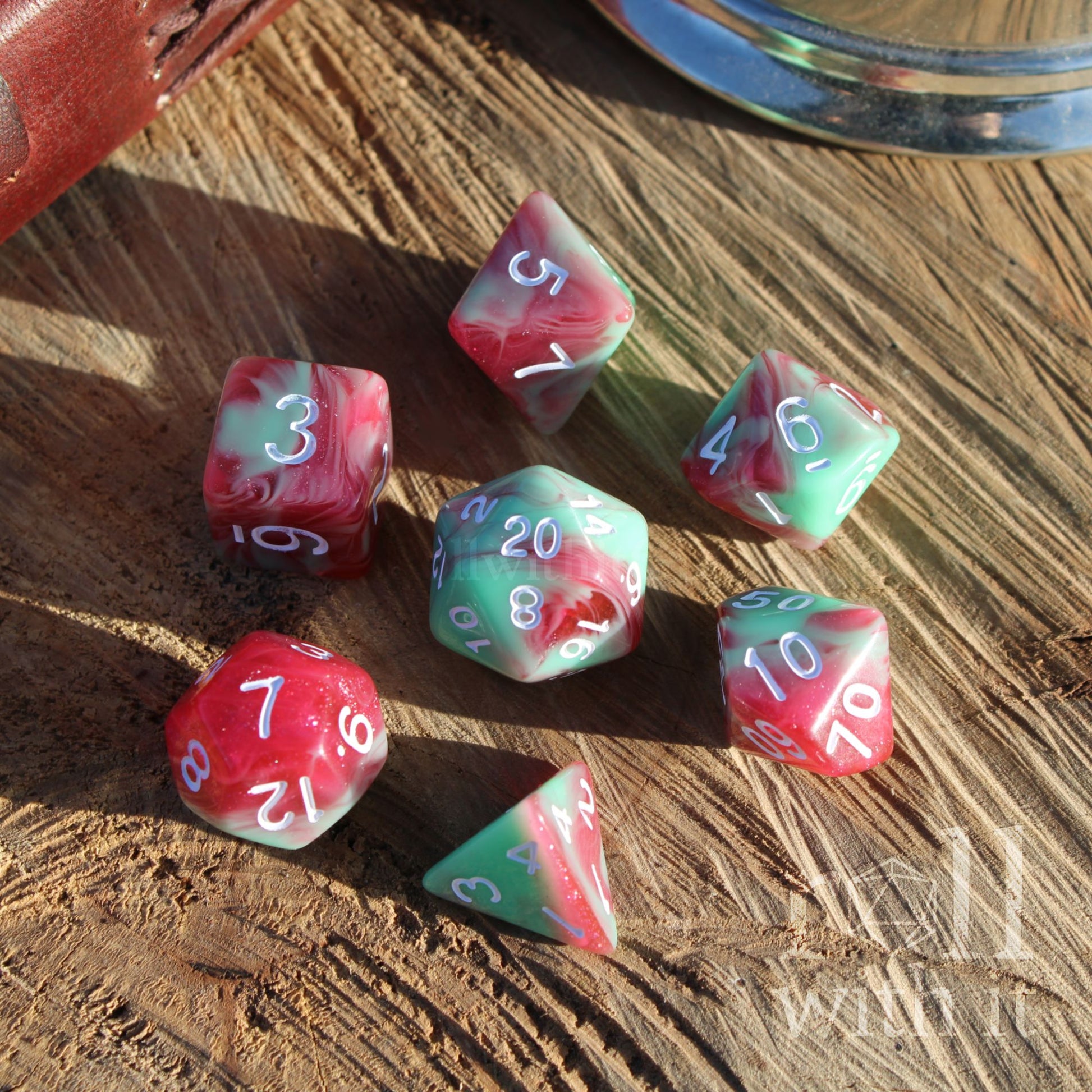 Set of swirling glitter filled red and green polyhedral dice with white numbers on a wooden surface