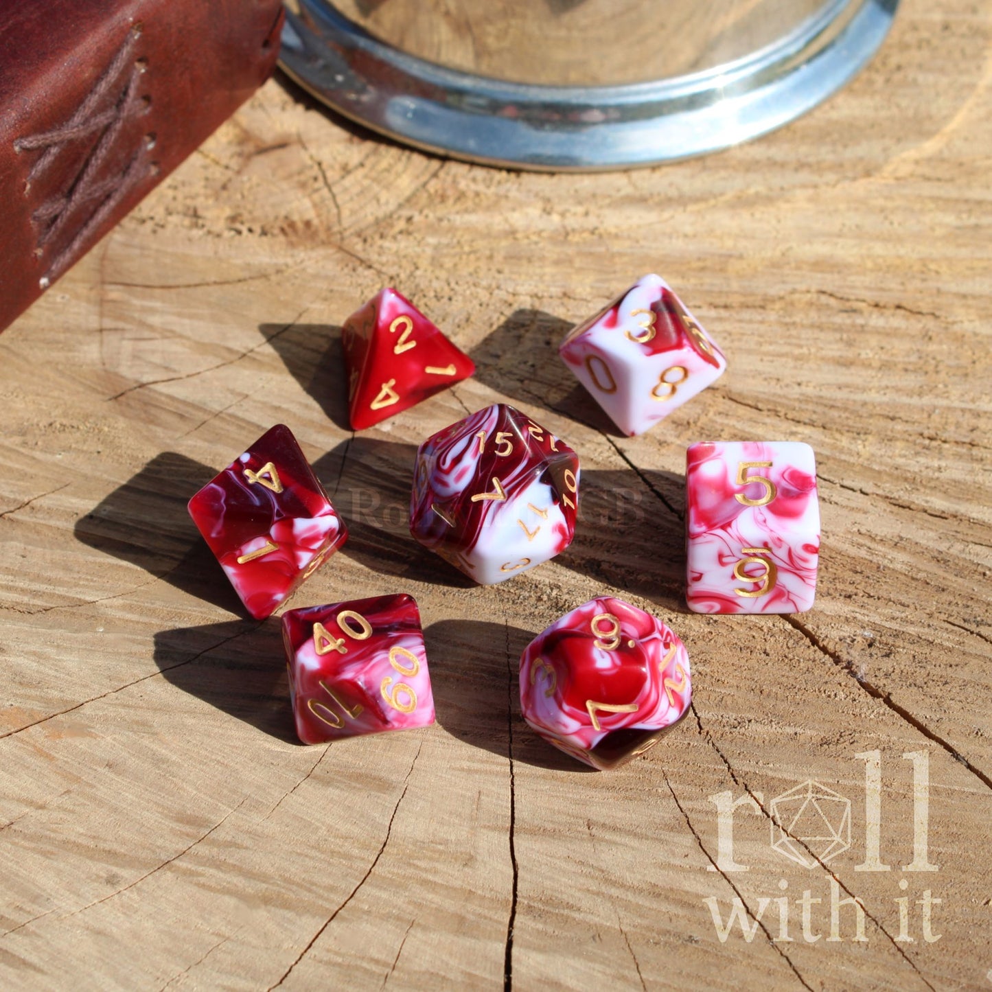 Set of red and white shiny TTRPG polyhedral dice on a wooden surface with 'roll with it' branding.