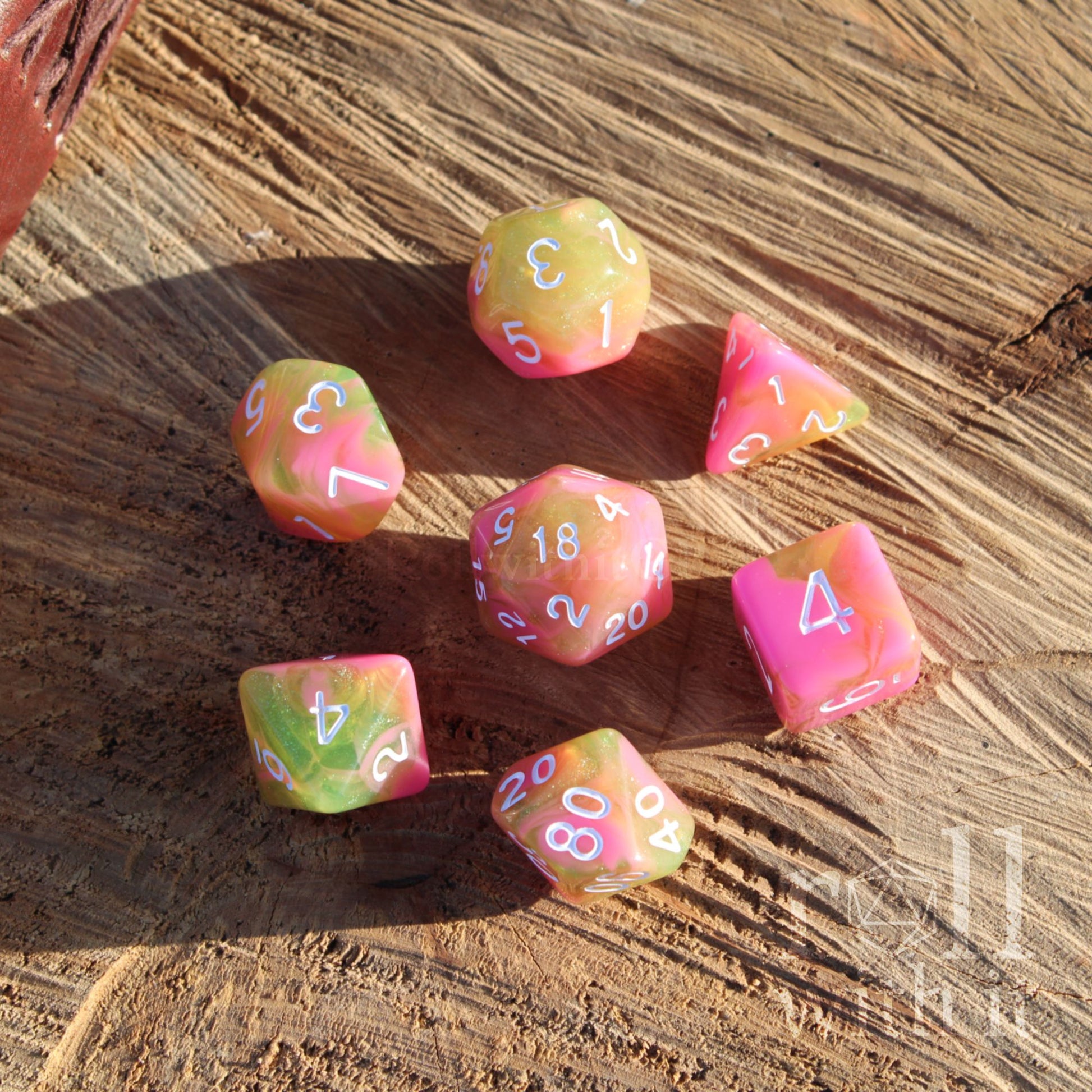 Set of 7 green pink mixed swirling glitter dnd dice on a wooden surface