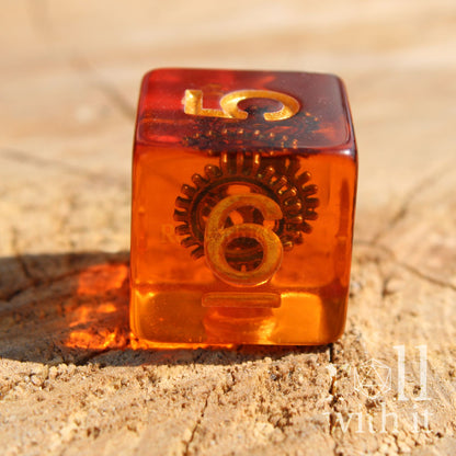 Translucent orange dice with gold numbers and a copper cog inside on a wooden background