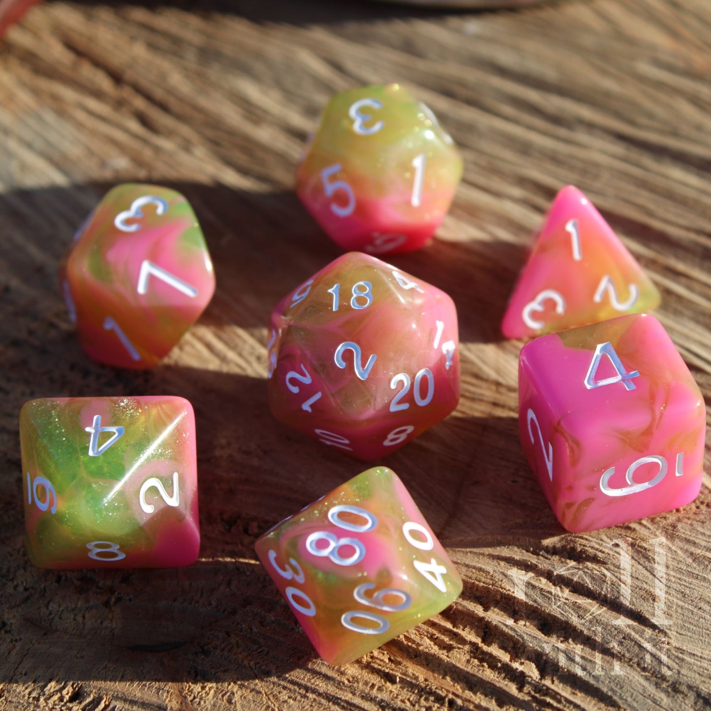 Set of colorful soft pink olive green cute polyhedral dice on a wooden surface