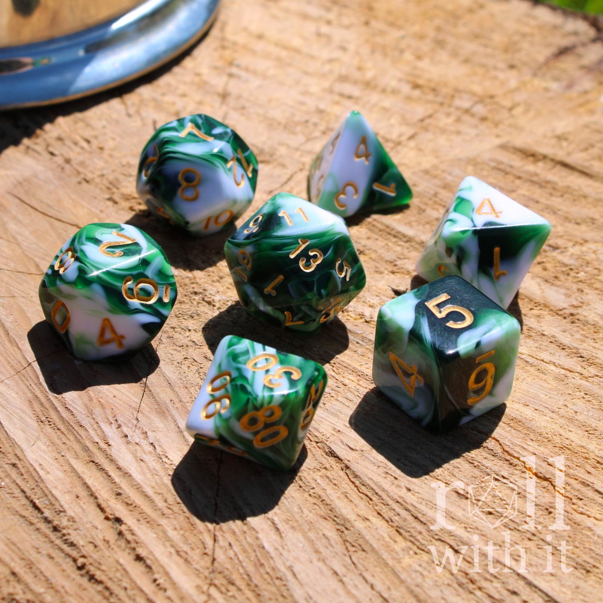 Set of green and white polyhedral dice on a wooden surface with 'Roll with It' branding.