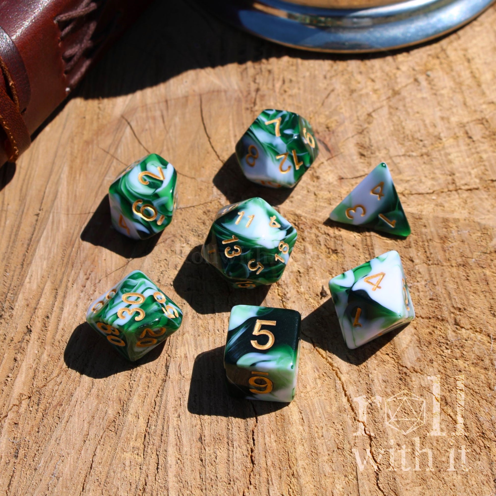 Set of green and white polyhedral dice on a wooden surface with 'roll with it' branding.