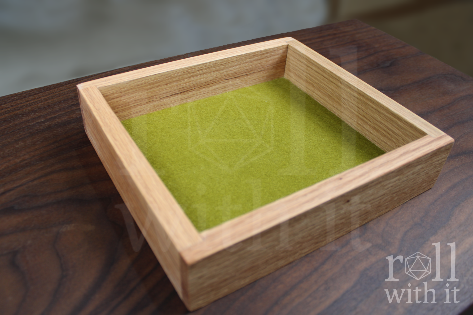 Wooden red oak roleplaying dice tray with green felt interior on a walnut table, featuring 'roll with it' logo.