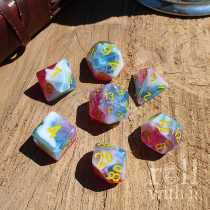 Set of colorful bright pink blue white milky mixed polyhedral dice on a wooden surface with 'roll with it' text.