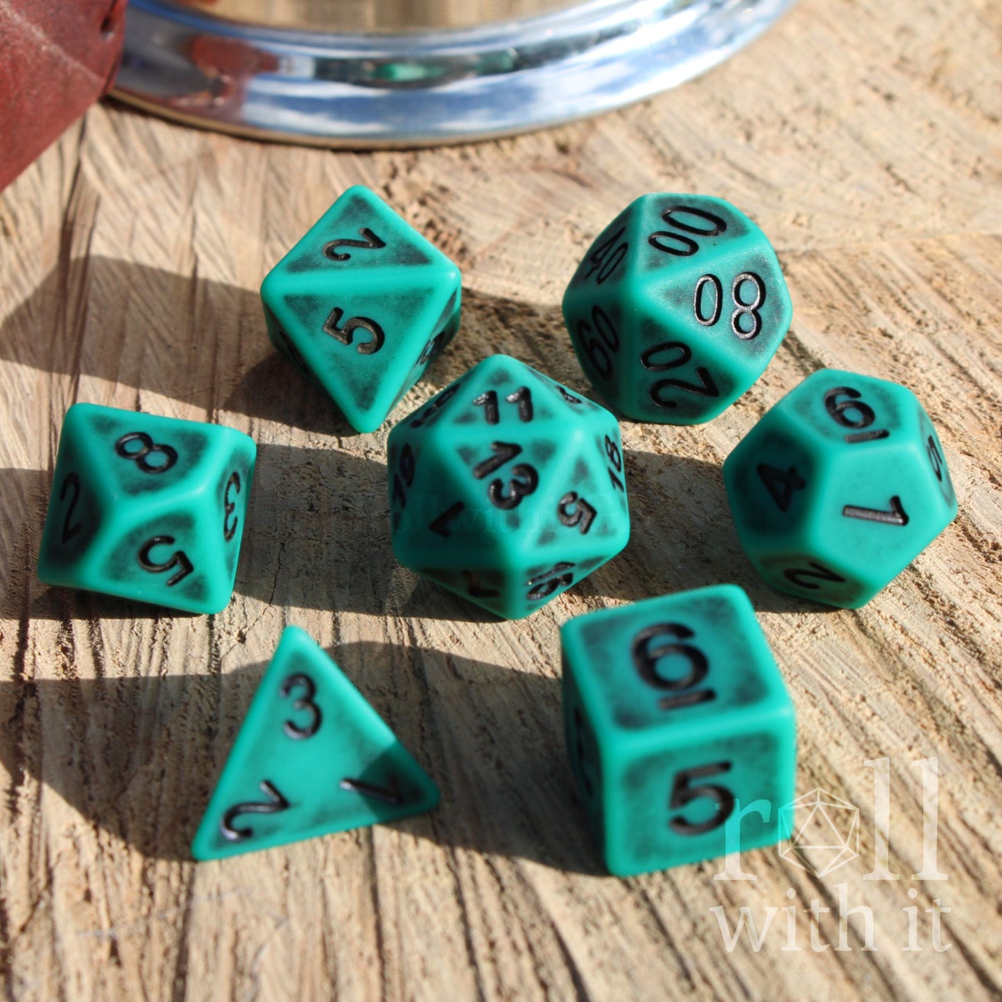 Set of teal matte DND polyhedral dice on a wooden surface