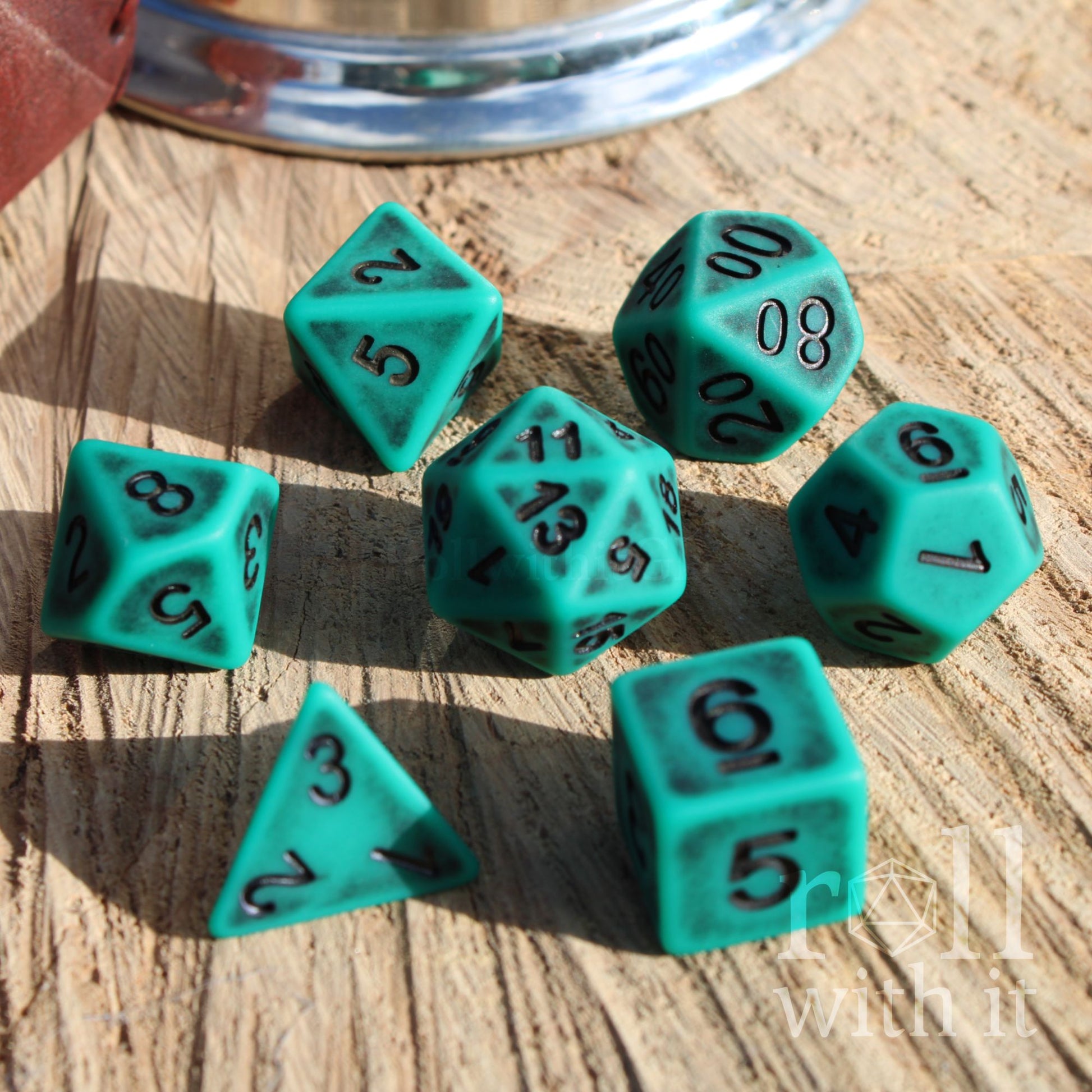 Set of teal matte DND polyhedral dice on a wooden surface