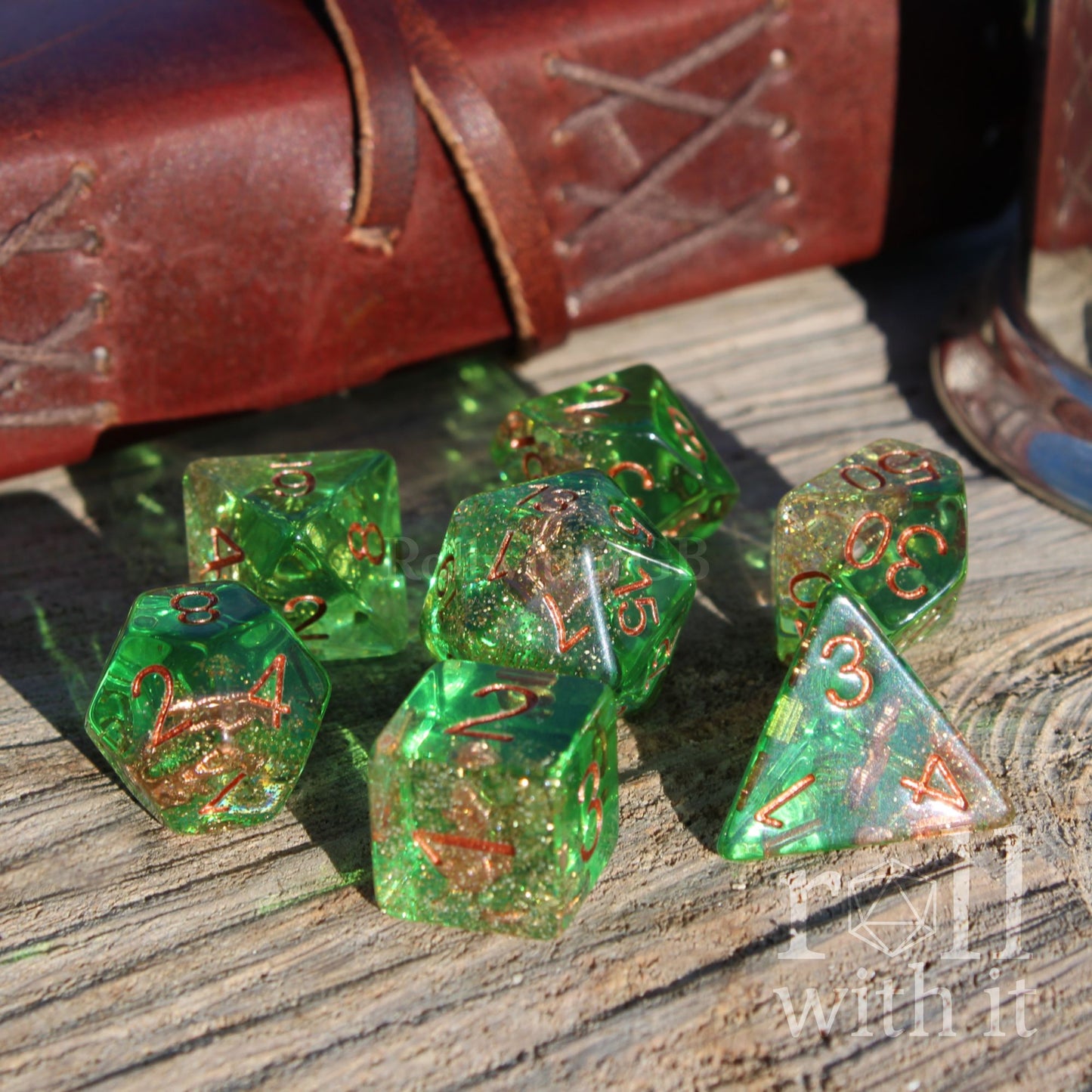 clear sea glass green polyhedral dice set with copper numbers on a wooden surface, with a leather-bound book in the background.