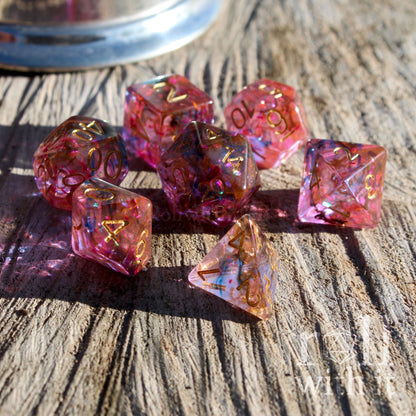 Set of pink and purple mixed foil reflective polyhedral dice on a wooden surface