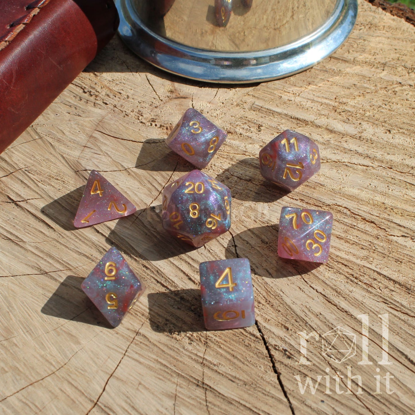 Set of full purple blue glitter dice with 'roll with it' text on a wooden surface