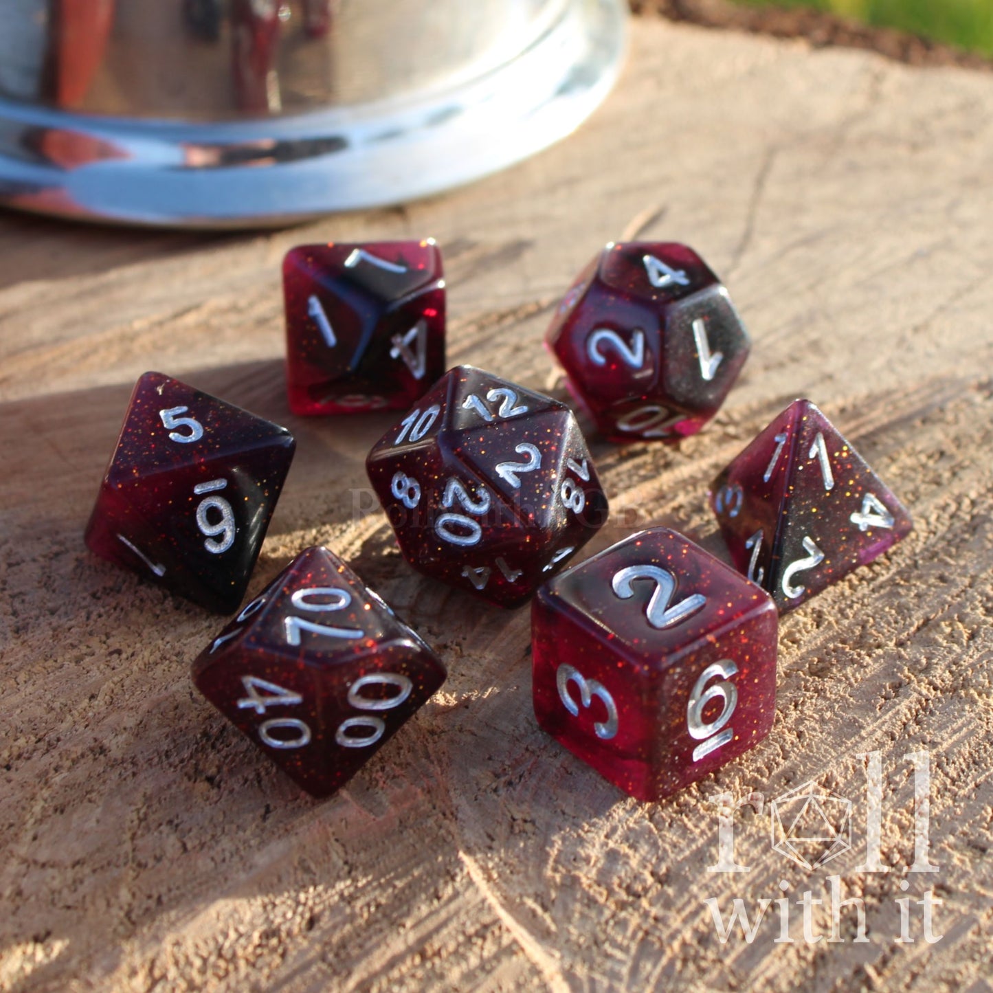 Set of red maroon garnet coloured and black polyhedral dice on a wooden surface with silver numbers