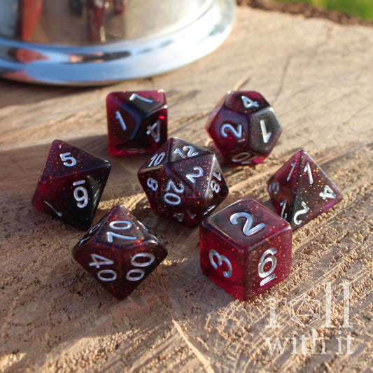Set of red maroon garnet coloured and black polyhedral dice on a wooden surface with silver numbers