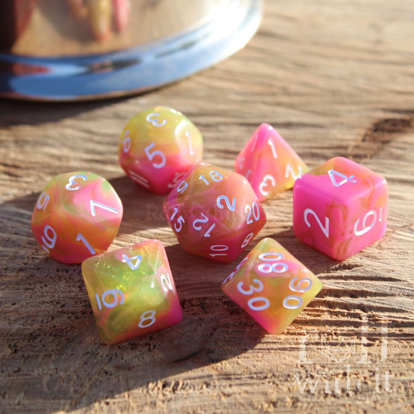 Bright pink green girly dnd dice set glittery white numbers on a wooden surface.