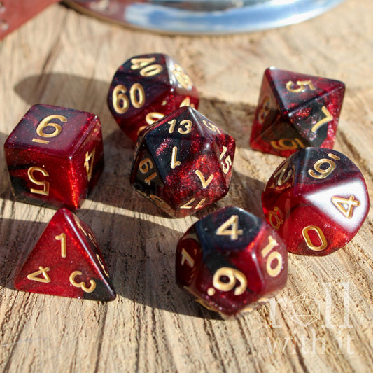 Set of red and black polyhedral starry glitter filled dice with gold numbers on a wooden surface