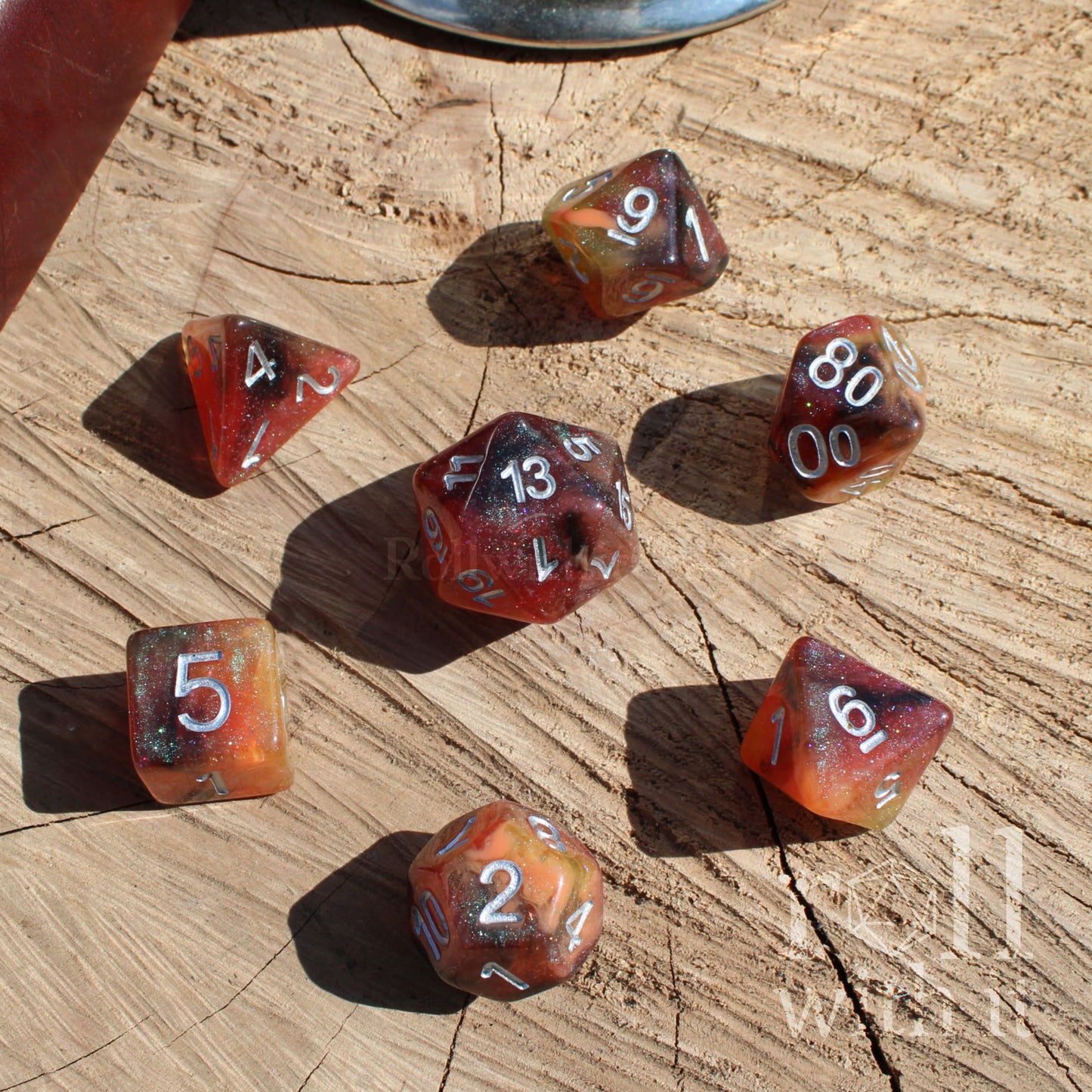 Set of mixed brown orange yellow green glittery polyhedral dice on a wooden surface