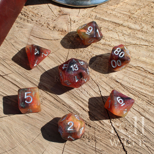 Set of mixed brown orange yellow green glittery polyhedral dice on a wooden surface