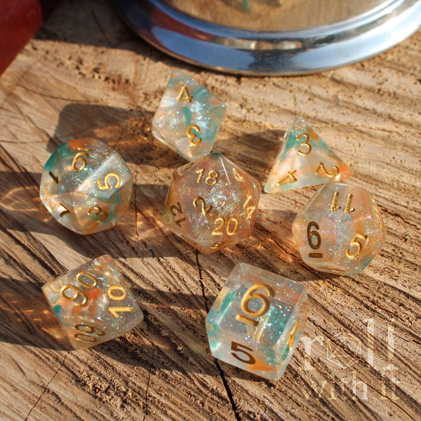 Set of transparent teal green blue orange fish scale dice with gold numbers on a wooden surface