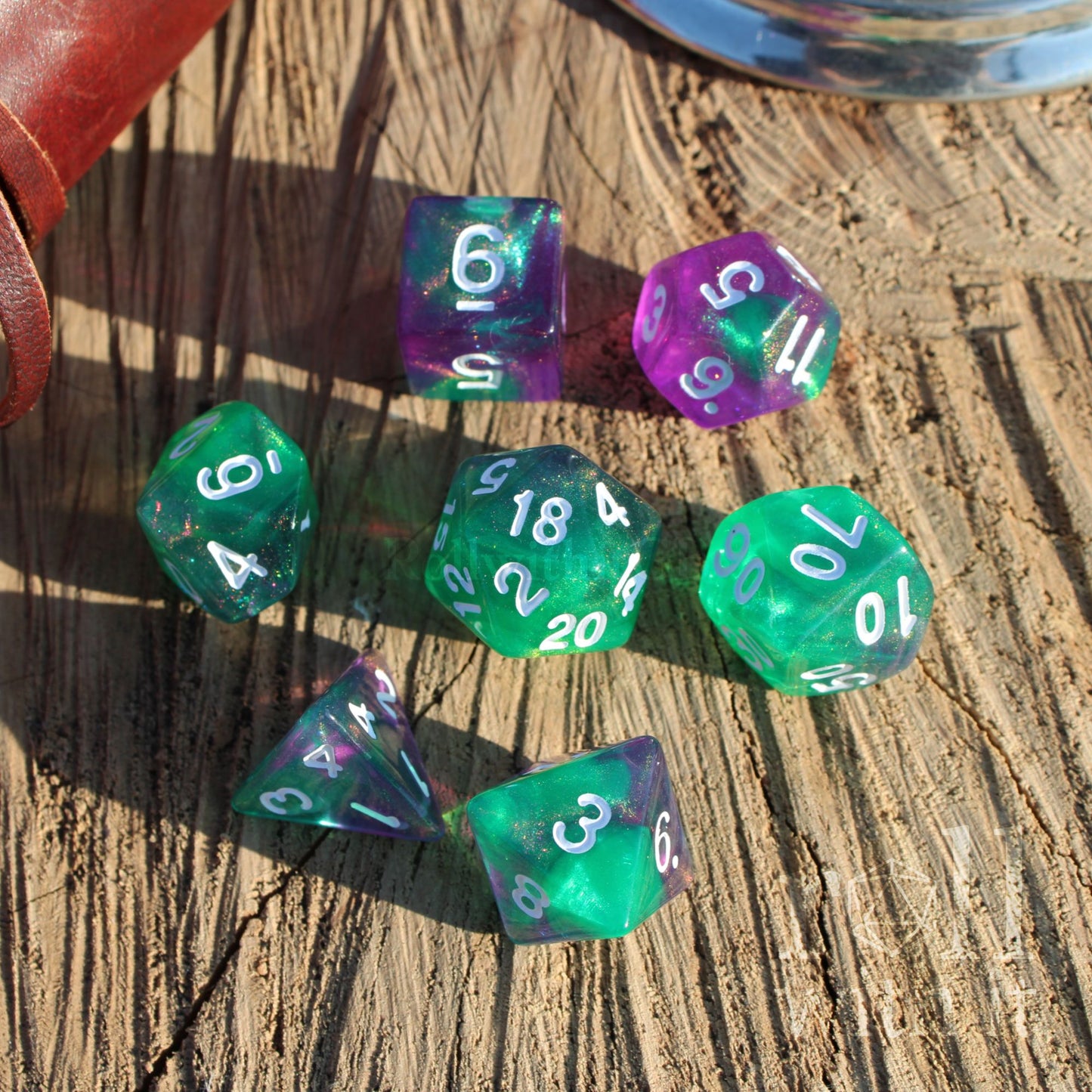 Set of green and purple glitter mixed shiny polyhedral dice on a wooden surface