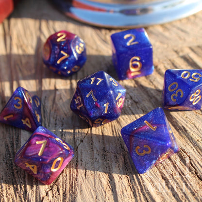 Set of blue and purple RPG polyhedral dice with gold numbers on a wooden surface.