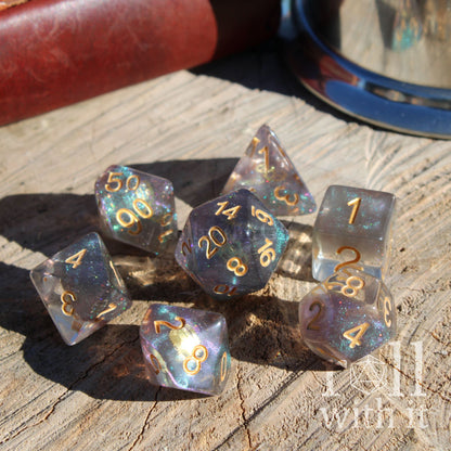 side view of 7 polyhedral dnd playing dice filled with purple blue glitter shining reflective with gold numbers and with gold cogs inside