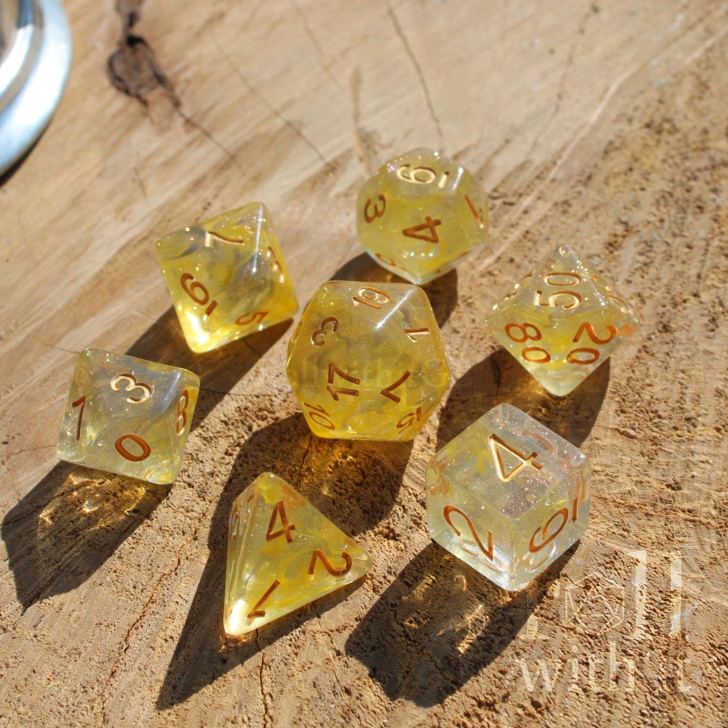 Set of yellow golden mixed grey glitter  polyhedral dice on a wooden surface