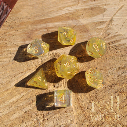 Set of transparent golden yellow flame and grey swirled glitter dice with numbers on a wooden surface
