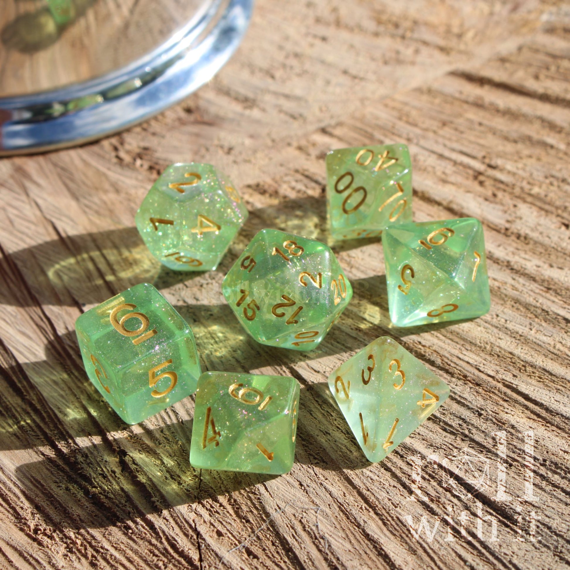 Set of bright green clear polyhedral dice with easy to read gold numbers on a wooden surface