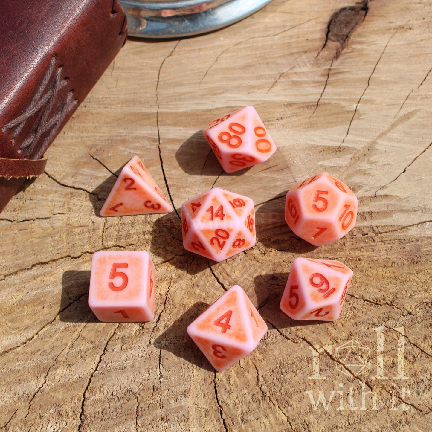 Set of pink polyhedral dice with hot pink numbers on a wooden surface