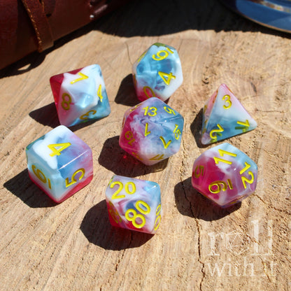 Set of colorful icecream pink white light sky blue polyhedral dice on a wooden surface with 'roll with it' text.