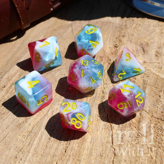 Set of colorful icecream pink white light sky blue polyhedral dice on a wooden surface with 'roll with it' text.