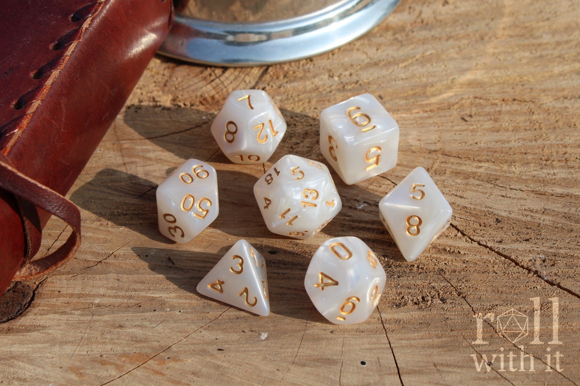 Pearl like white DnD tabletop roleplaying dice with gold numbers on a wooden surface