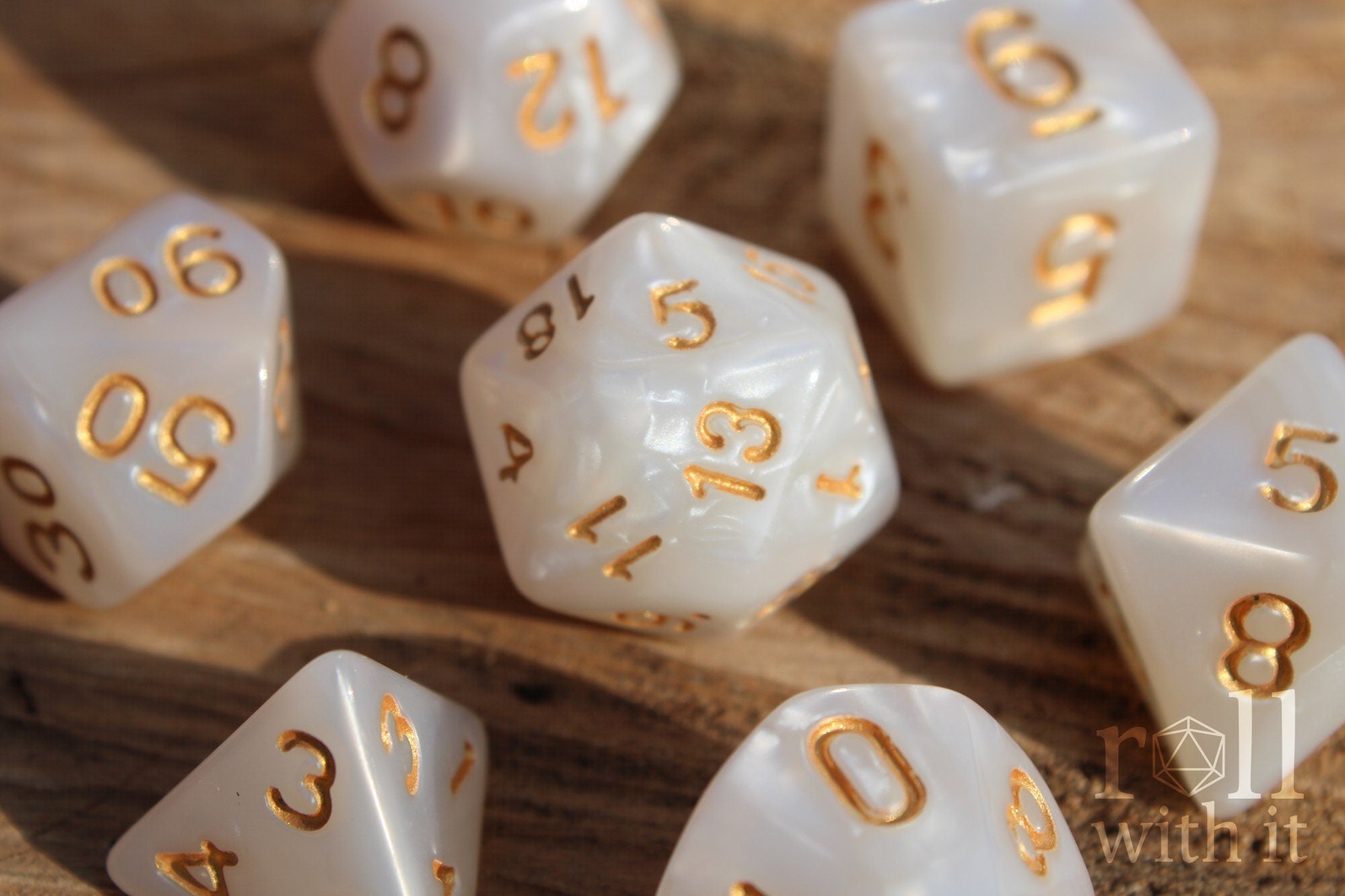Pearlescent white DnD roleplaying dice with gold numbers on a wooden surface