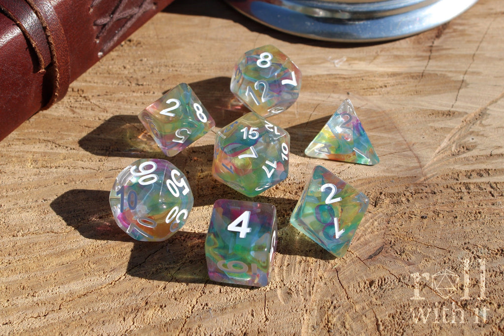 Set of colorful swirling rainbow and clear polyhedral dice on a wooden surface